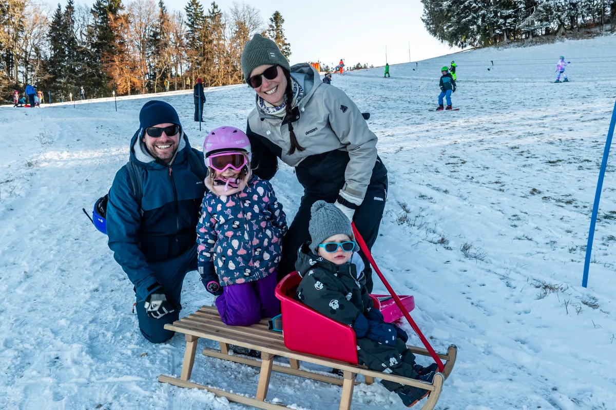 Man sieht eine Familie mit einem Schlitten. 
